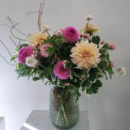 Mixed pink and cream flowers arranged in a glass vase