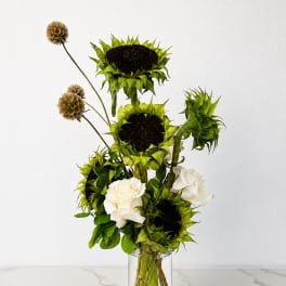 Tall arrangement of green sunflowers and white roses in a clear glass vase