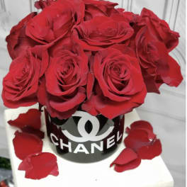 Red roses arranged in a black Chanel box with scattered petals