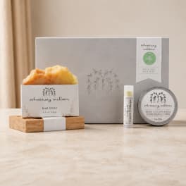 Bath and body gift set with soap, balm, and lip balm in a gray box