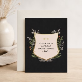 Black greeting card with a motivational quote and floral border, leaning against an envelope