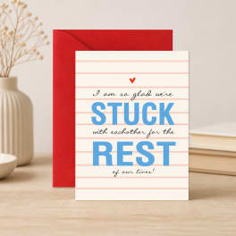 Greeting card with the words "STUCK REST" in blue, leaning against a red envelope