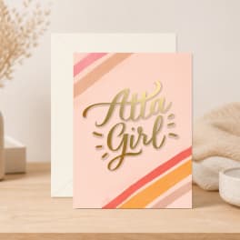 Pink greeting card reading "Atta Girl" with envelope behind it