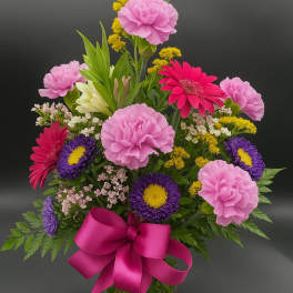 Colorful mixed bouquet in a glass vase with a pink ribbon