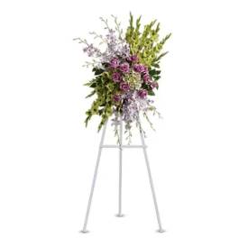 Tall floral spray on a white easel with purple flowers and green accents
