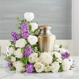 White and purple floral arrangement around a silver urn