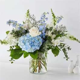 Blue hydrangeas and white roses in a clear glass vase