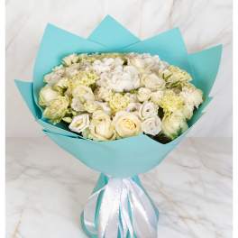 Bouquet of white roses and pale cream flowers wrapped in turquoise paper