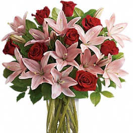 Bouquet of red roses and pink lilies in a clear glass vase