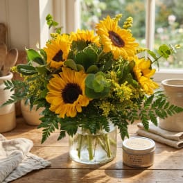 Sunflower bouquet in a clear glass vase with greenery and yellow filler flowers