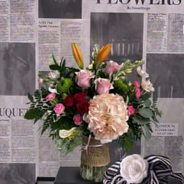 Mixed bouquet in a glass vase with pink roses, lilies, and hydrangea