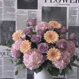 Pink and lavender bouquet with peach daisies in a white vase