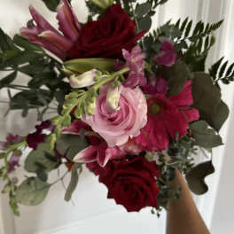 Handheld bouquet of red and pink flowers with eucalyptus