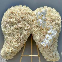 Heart-shaped floral tribute of cream roses with white orchids on an easel