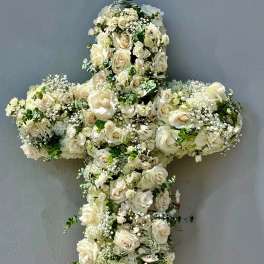 White floral cross arrangement on an easel