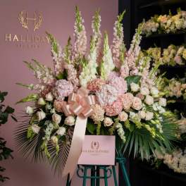 Large pastel floral arrangement with pink and white blooms and a satin ribbon