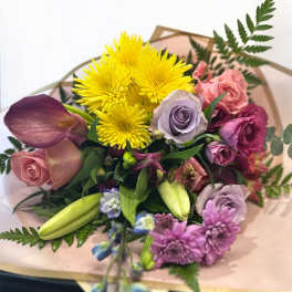 Mixed bouquet with yellow chrysanthemums, roses, and lilies wrapped in paper