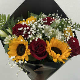 Bouquet of red roses and sunflowers with white filler flowers in black wrap