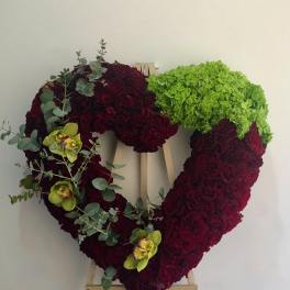 Heart-shaped floral wreath on an easel with burgundy and green blooms