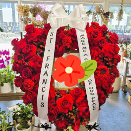 Large red rose funeral wreath with white ribbons on a stand