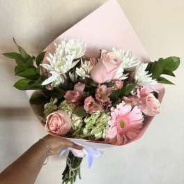 Pink and white bouquet with roses, daisies, and hydrangeas wrapped in pastel paper