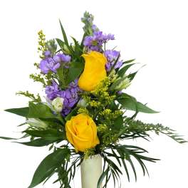 Yellow roses and purple flowers arranged in a tall white vase
