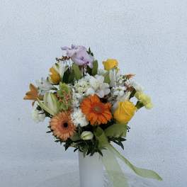 Mixed bouquet in a white vase with yellow, orange, white, and lavender blooms