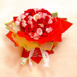 Bouquet of red and pink roses wrapped in red paper with ribbons