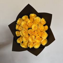 Bouquet of yellow roses wrapped in dark paper
