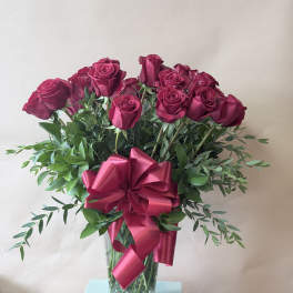 Bouquet of deep pink roses in a glass vase with a large ribbon