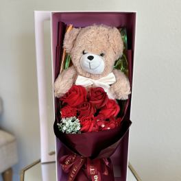 Teddy bear with red roses in a gift box