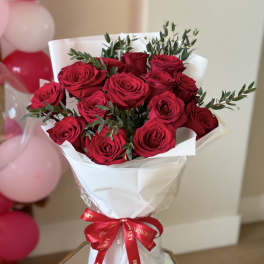 Bouquet of red roses wrapped in white paper with a red ribbon