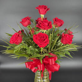 Red roses arranged in a clear glass vase with a red ribbon bow