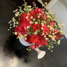 Red rose bouquet with small white daisy-like flowers in a white holder