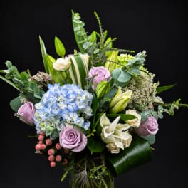 Mixed bouquet of pastel roses, hydrangea, and lilies in a glass vase