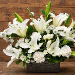 White lilies and small white flowers arranged in a rectangular container