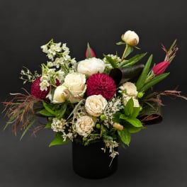 Mixed bouquet of white and deep pink flowers in a black vase