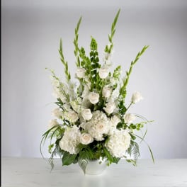 Tall white floral arrangement in a white bowl vase with roses and greenery