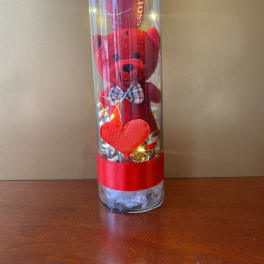 Red teddy bear in a clear tube with a heart and ribbon