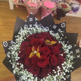 Bouquet of red roses with white baby's breath in black patterned wrap