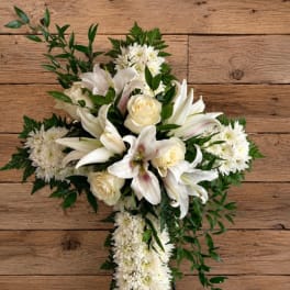 White floral standing spray on an easel with lilies, roses, and chrysanthemums