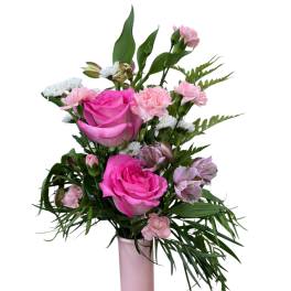 Pink roses and mixed blooms arranged in a tall pink vase