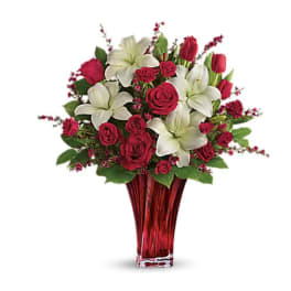 Bouquet of red roses and white lilies in a red glass vase