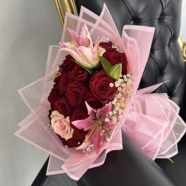 Bouquet of red roses and pink lilies wrapped in pink paper