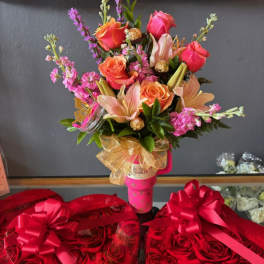 Pink and orange bouquet in a pink tumbler, with heart-shaped rose boxes below.