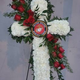 Cross-shaped floral tribute with white blooms and red roses on an easel