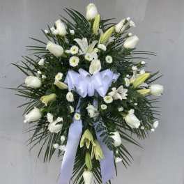 White floral standing spray with lilies and roses on a ribboned easel