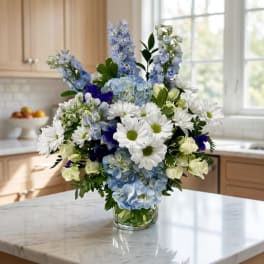 Blue and white mixed bouquet in a clear glass vase