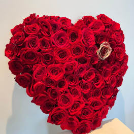 Heart-shaped arrangement of red roses on a white pedestal