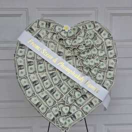 Heart-shaped money display with a white ribbon and small flower accent